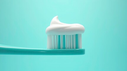 Close-up macro shot of a turquoise toothbrush with white and teal bristles topped with a perfectly swirled line of white toothpaste.
