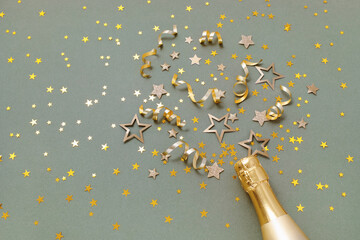 Obraz premium Party, New Year or birthday festive background with golden champagne bottle and confetti stars. Trendy green card for holiday celebration top view.
