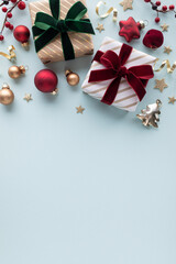Beautiful golden gift or present boxes with velvet red and green ribbon with festive decoration on light blue background for Christmas or New Year greeting card