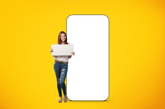 Happy young student woman holding signboard and huge smartphone