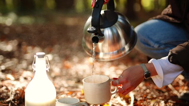 A person is pouring water into a white cup while standing in a forest. The scene is peaceful and serene, with the person enjoying a moment of relaxation in nature