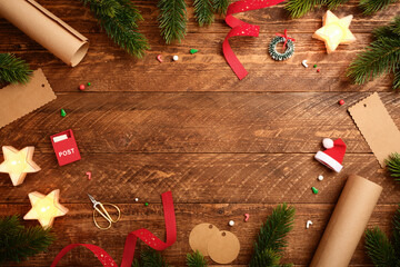 Christmas frame with star candles, wrapping paper, fir spruces, gift tags on wooden background. Copy space for text or design.