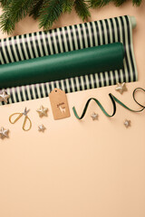 Christmas wrapping paper rolls, brown gift tag, and gold stars on beige background. Copy space for your text or design.