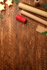 Christmas wrapping background with paper rolls, rope, gift tags and scissors on dark wooden desk. Copy space for text.