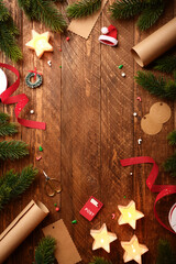 Christmas frame with star candles, wrapping paper, fir spruces, gift tags on wooden background. Copy space for text or design.