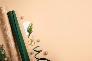 Gift wrapping background. Paper rolls, gift tag, and gold stars on beige desk. Copy space for holiday text or design.