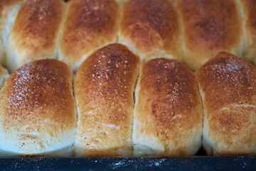 Homemade freshly baked soft buns with filling, close-up, on a baking sheet held by a woman. Selective focus. Close-up