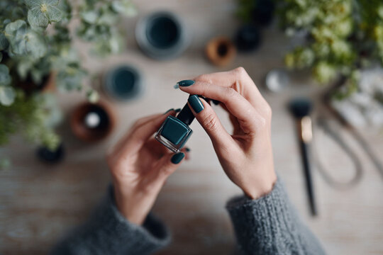 Woman holds teal nail polish bottle. A serene, lifestyle scene perfect for beauty blogs, selfcare promotions, cosmetic marketing, or feminine empowerment messages.