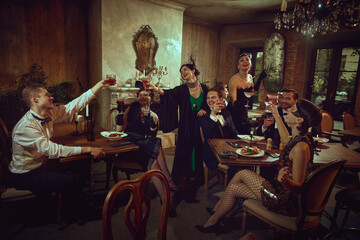 Joyful vintage celebration with friends raising glasses in warm interior. Concept of holiday marketing, gala dinner promo, themed party creatives, premium beverage ads, event agency materials.