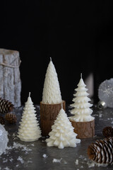 Burning candle in shape of Christmas tree and decor on dark background