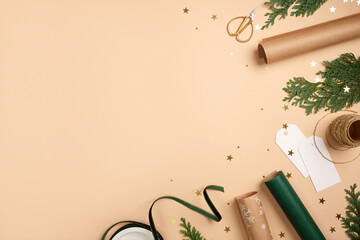 Gift wrapping background. Paper rolls, gift tag, and gold stars on beige table. Copy space for holiday text or design.