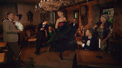 Retro dancer raising arms under chandelier while friends relax in elegant vintage bar. Concept of themed glamour evenings, nightlife campaigns, entertainment posters, luxury event visuals.