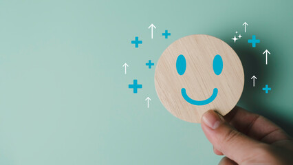 Mental health and emotional wellbeing concept with a smiling wooden face and positive symbols,...