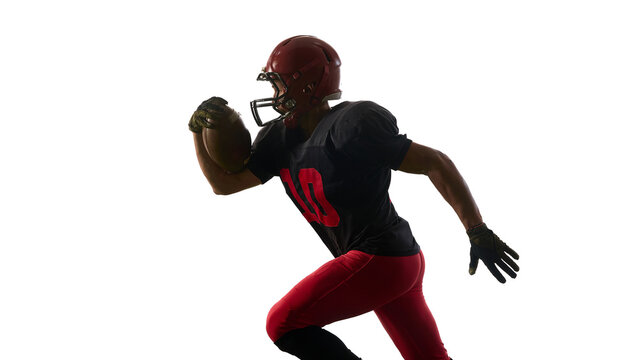 American football player sprinting with powerful focused emotion holding ball isolated on white background. Concept of speed training, athlete marketing, technique tutorials.