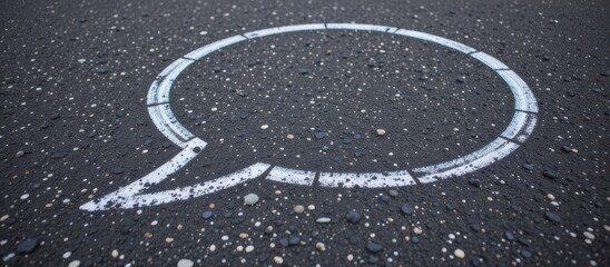 A speech bubble outline on a textured asphalt surface.