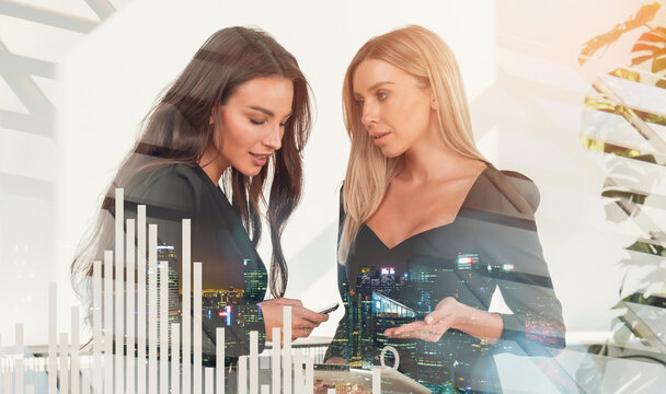 Two professional women in formal attire discussing business strategy, double exposure of cityscape and bar chart, concept of teamwork and modern analytics