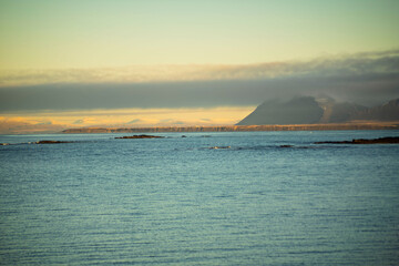 Distant Mountains and Calm Sea Under Low Clouds at Sunset