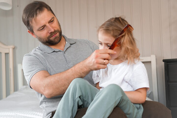 Man brushing daughters hair. Daddy combing girl's hair at home. Responsible good dad braiding his child girl's hair. Handsome father grooming his little one. Morning routine concept. Family life