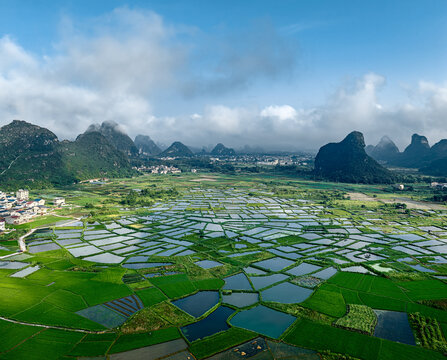 Aerial view of green agriculture fields and karst mountains under blue sky in Guilin. - Powered by Adobe