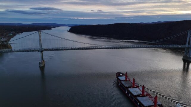 Aerial view of the Mid-Hudson Bridge spanning the Hudson River with a large cargo ship passing underneath, Poughkeepsie, New York, United States.