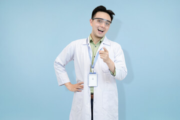 Confident Asian scientist or doctor in a lab coat and safety goggles, pointing directly forward,...