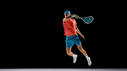 Athletic man jumping for strong tennis shot in professional studio lighting. Concept of advertising visuals, product promotion, design compositions, and creativity in sport motion.
