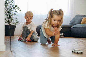 Naklejka premium Small cars, fun. Little kids are playing together in the domestic room at daytime