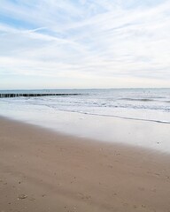 Fototapeta premium lonely beach with waves and sky in zeeland, the netherlands