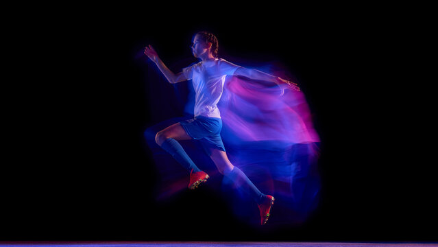 Female soccer player sprinting in neon light motion trail. Concept of fitness campaign visuals, sportswear brand advertising, and coaching materials for speed and agility drills.