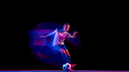 Female football player controlling ball with precision under lights. Concept of ball mastery training, fitness campaign visuals, sportswear marketing, and athlete education.