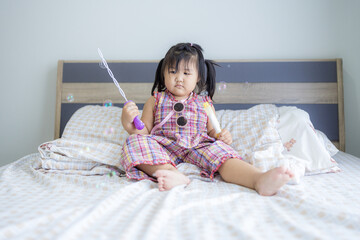 A cute little Asian girl is having fun blowing soap bubbles inside her house,portrait of cute girl having fun with soap bubbles at home.