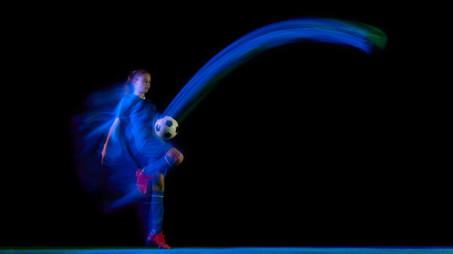 Female athlete juggling soccer ball in blue-green light motion blur. Concept of football skill training, motion design, sport education, and fitness campaign visuals.