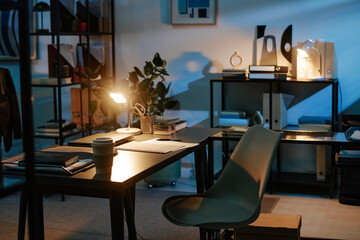 Empty modern office with documents scattered on desk and chair pushed back suggesting recent...