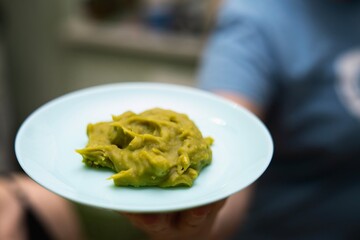 Woman holding blue ceramic bowl with homemade pea praline during lunch at home