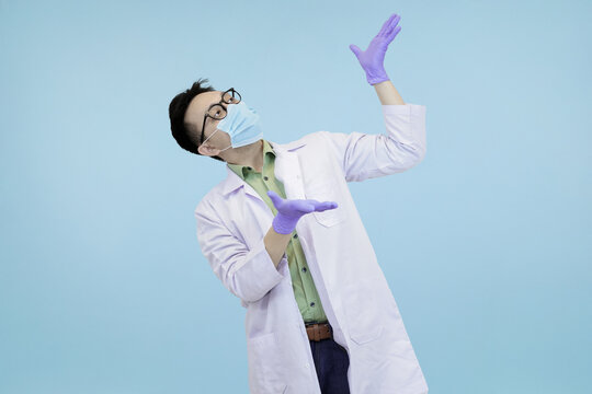 Asian scientist or doctor wear lab coat holding a folder, pointing to empty space, signifying presentation, explanation, or a new direction in blue studio background