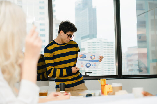 Young man holding a document displaying pie charts and graphs, D