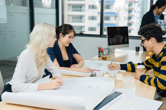 Diverse professionals work together, drawing and discussing large architectural blueprints and technical drawings. team plans project development, execution in a modern, collaborative office setting.
