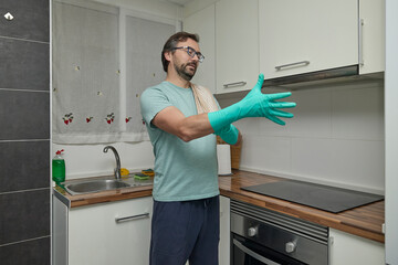 Man putting on rubber gloves in modern kitchen before cleaning. Person preparing for housework,...