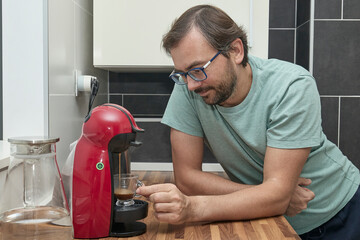 Man making coffee with coffee machine in modern kitchen. Person preparing espresso at home and enjoying a fresh cup of coffee. Concept of morning routine, home comfort, and caffeine energy