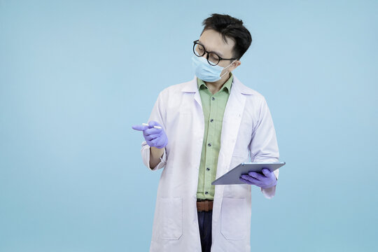 An Asian scientist or doctor looking intently at a digital tablet, symbolizing deep focus on data, analysis, or identifying a critical issue in blue studio background - Powered by Adobe
