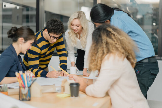 Diverse startup team actively collaborating and drawing on techn