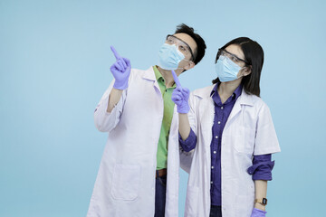 Asian medical pointing upwards, signifying instruction, attention, or a new successful direction in blue studio background