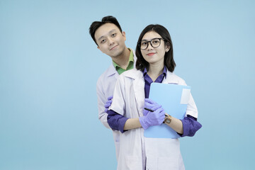 Astonished Asian science professionals reacting to a breakthrough, excitedly viewing data on a digital tablet during research in blue studio background