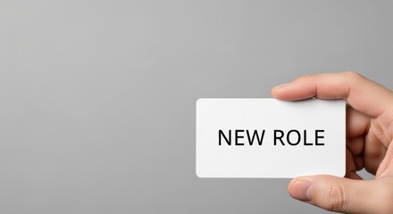 Close-up of a hand holding a small white card with the words New Role, representing career advancement, a job promotion, or a change in professional responsibilities