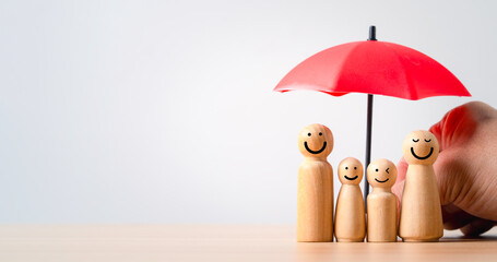 Wooden family figures under a red umbrella representing insurance protection safety support and well being with copy space suitable for financial security concepts and family care themes