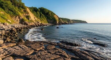 Coastal scene with rocky shore, cliffs, and ocean under a clear, bright sky