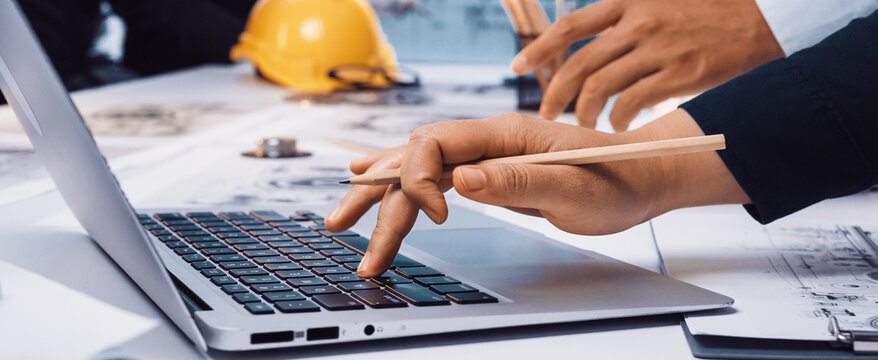 A diverse team collaborates in a modern office environment, using a laptop and engineering tools to facilitate project planning and creative discussions. SACTR - Powered by Adobe