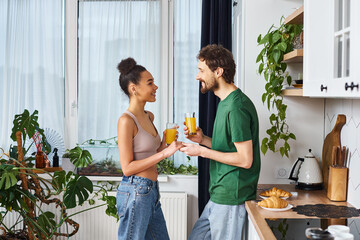 Cozy moment shared between a young couple in a bright, plant filled kitchen