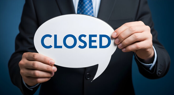 Businessman in suit holding a speech bubble with the word "closed" in blue signaling business closure or shop closing financial difficulties or a company going out of business