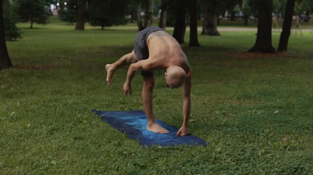 Man performing smooth mobility and roll transitions barefoot outdoors